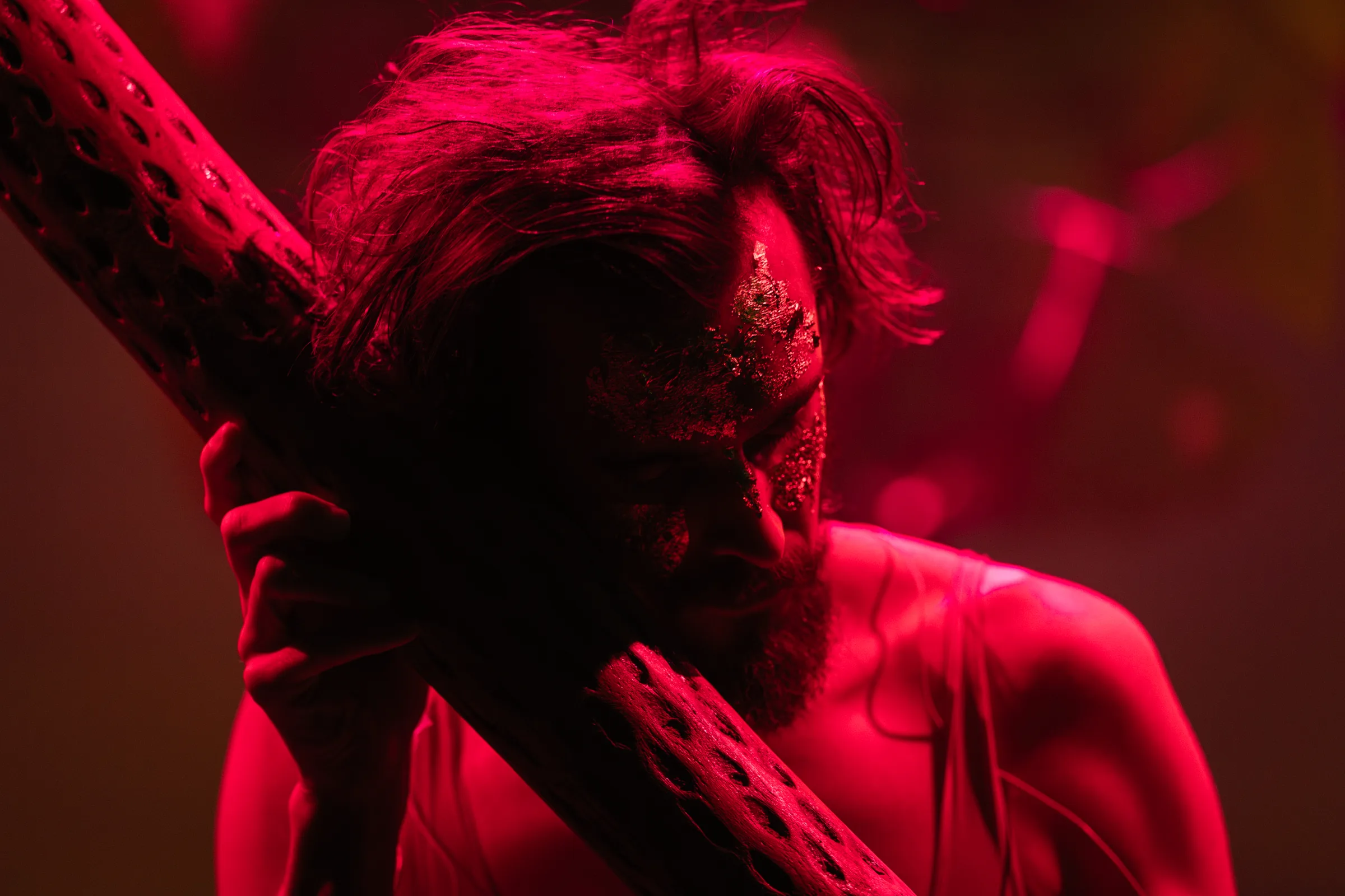 A performer holds a ceramic form under saturated red stage light.